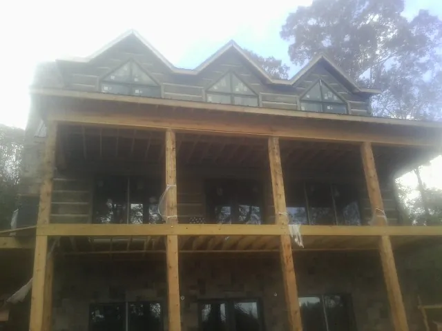 Dormers and porch framing on a large log home under construction — Roof Coating work by our crew in Granville